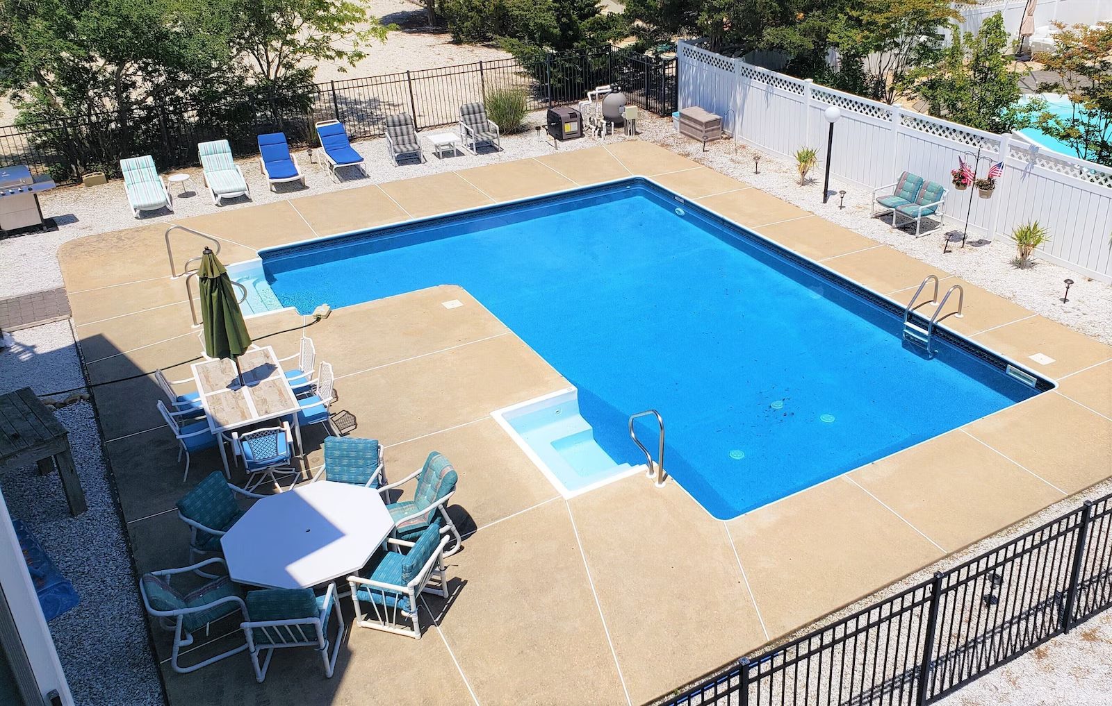 Rectangular swimming pool with tiled deck and lounge chairs